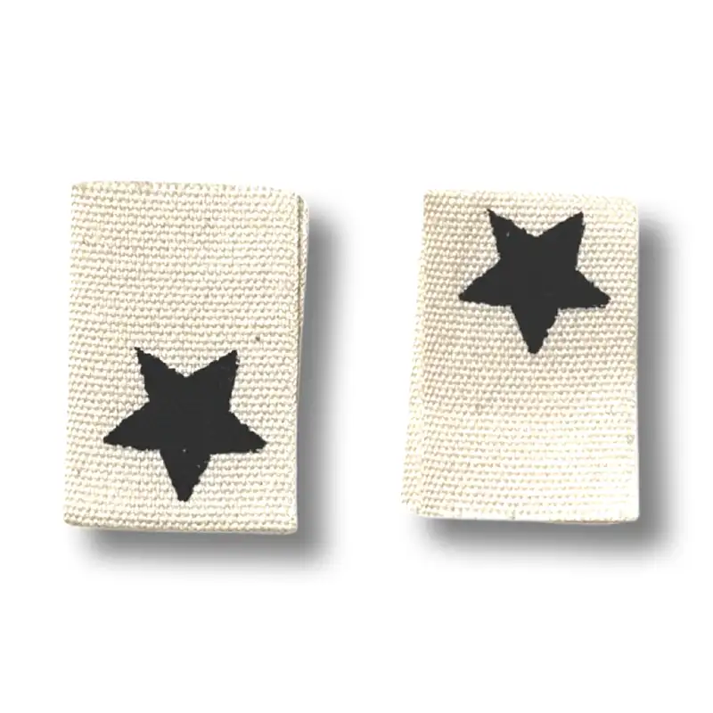 2 rechteckige Baumwoll-Labels mit schwarzen Sternaufdruck.